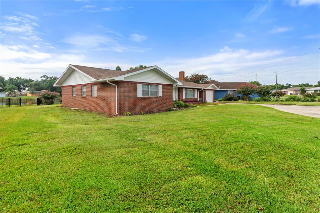 A single-story brick house with a gabled roof sits on a large grassy lawn — 404 COLEMAN DRIVE, WINTER HAVEN, FL