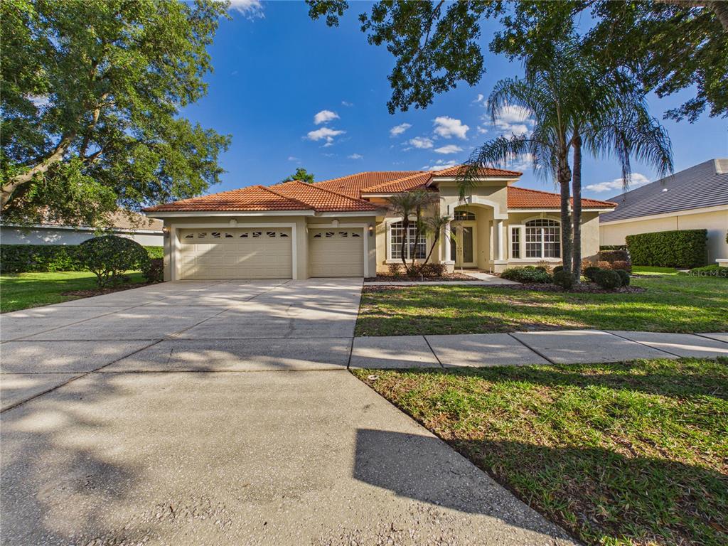 A single-story house with a tile roof, three-car garage, and a palm tree in front — 10207 ESTUARY DRIVE, TAMPA, FL