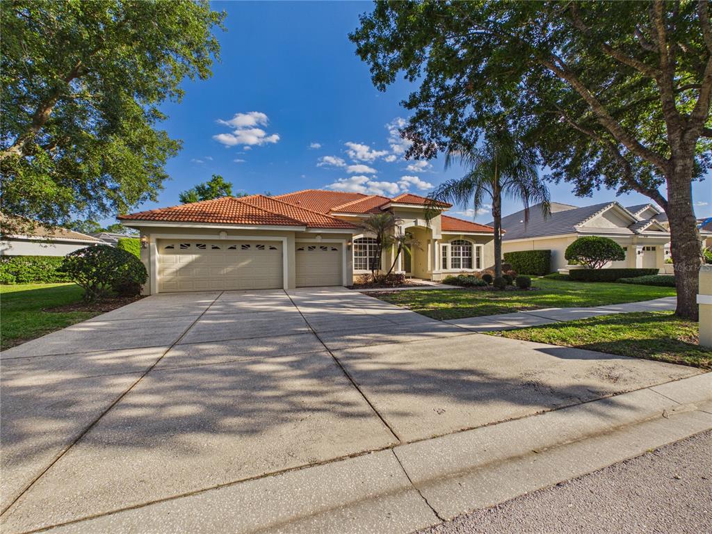A single-story house with a tile roof, two-car garage, and a large tree in front — 10207 ESTUARY DRIVE, TAMPA, FL