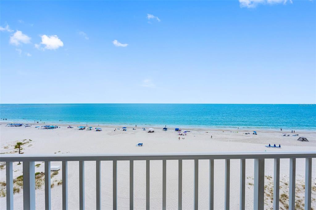 A view of a sandy beach and the ocean from a balcony with white railings — 13500 GULF BOULEVARD UNIT 605, MADEIRA BEACH, FL