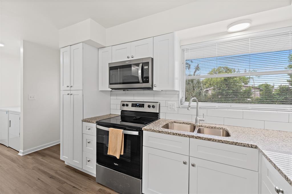 A kitchen features white cabinetry, stainless steel appliances, granite countertops, and a window above the sink — 815 GLADE ROAD, TITUSVILLE, FL