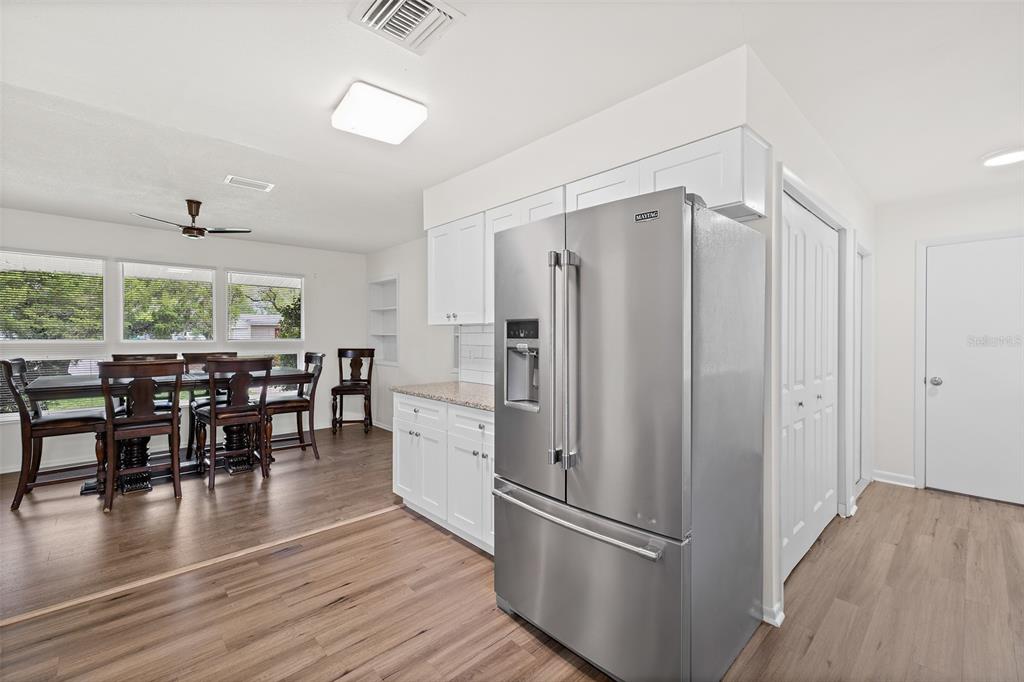 A kitchen with white cabinets and stainless steel appliances opens into a dining area — 815 GLADE ROAD, TITUSVILLE, FL