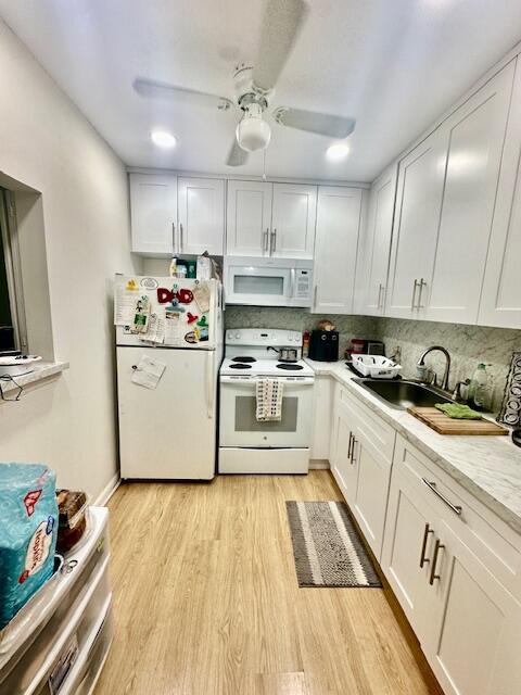 A kitchen features white cabinets, stainless steel appliances, and light wood-look flooring — 583 Fanshaw, Boca Raton FL 33434, BOCA RATON, FL