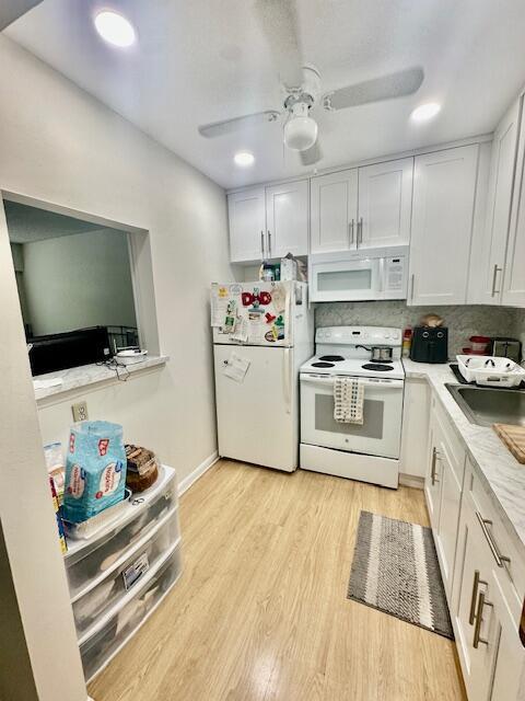 A small kitchen features white cabinets, stainless steel appliances, and light wood-look flooring — 583 Fanshaw, Boca Raton FL 33434, BOCA RATON, FL