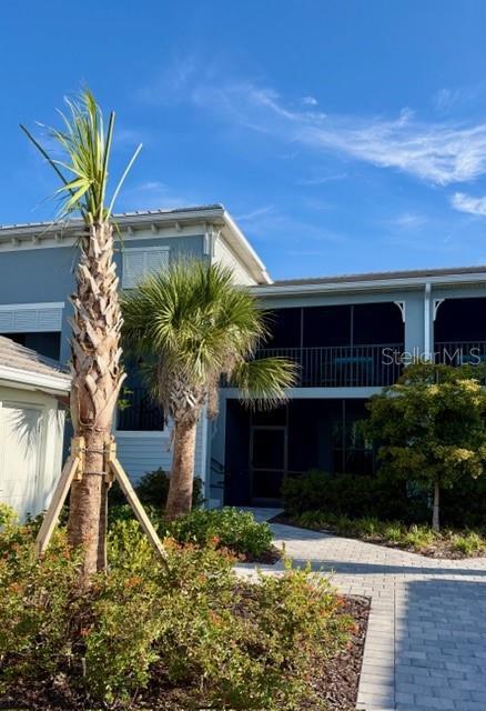 A paved walkway leads to the entrance of a two-story building with screened balconies — 17475 OPAL SAND DRIVE UNIT 204, VENICE, FL