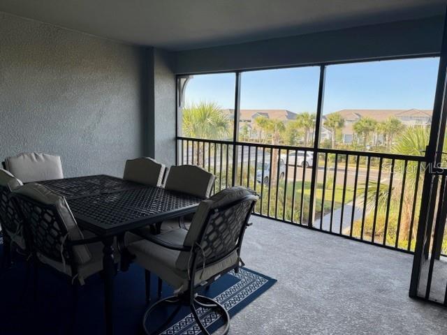 A screened-in balcony features a dining table and chairs overlooking a residential neighborhood — 17475 OPAL SAND DRIVE UNIT 204, VENICE, FL