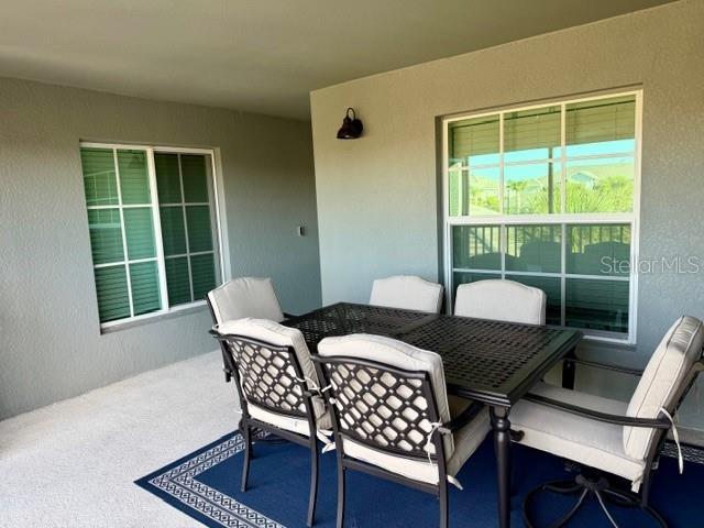 A covered patio features a dark metal dining set on a blue patterned rug — 17475 OPAL SAND DRIVE UNIT 204, VENICE, FL