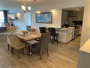 A dining area with a wooden table and chairs sits adjacent to a modern kitchen — 6039 Collins Ave # 1131, Miami Beach FL 33140, MIAMI BEACH, FL