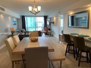 A dining area with a wooden table, chairs, and a bench leads into a living room — 6039 Collins Ave # 1131, Miami Beach FL 33140, MIAMI BEACH, FL