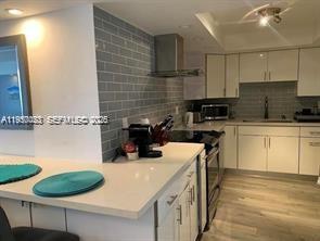 A modern kitchen features white cabinetry, a light-colored countertop, and a gray subway tile backsplash — 6039 Collins Ave # 1131, Miami Beach FL 33140, MIAMI BEACH, FL