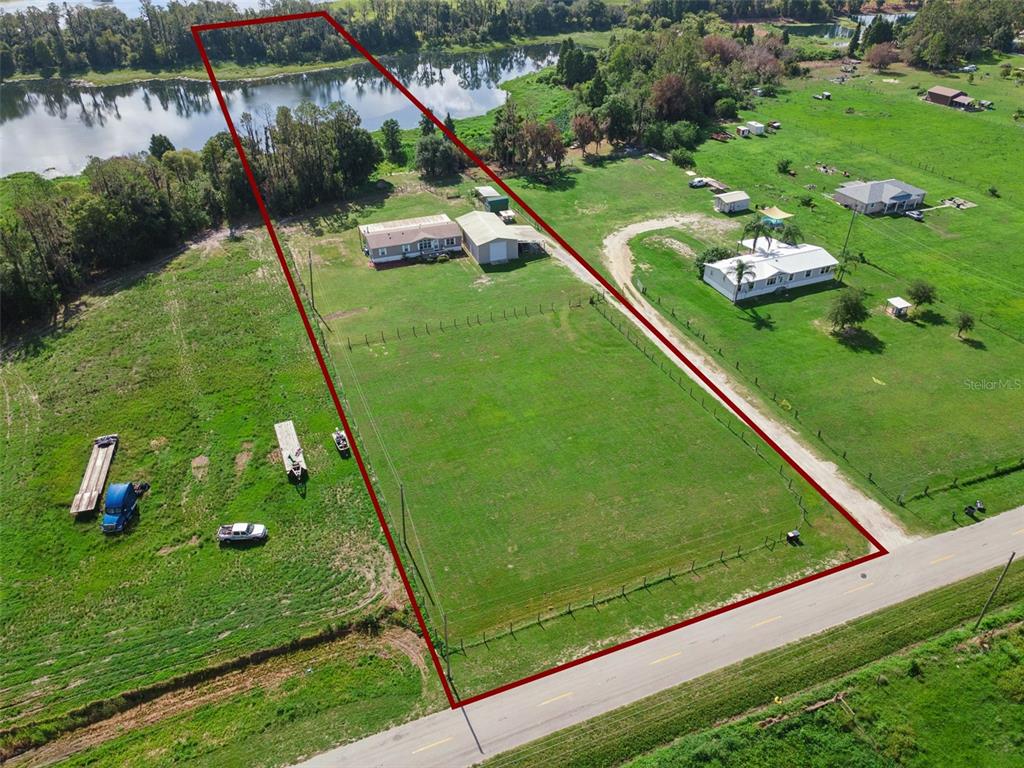 An aerial view shows a house and detached garage on a large, fenced grassy lot — 1153 SAND MOUNTAIN ROAD, FORT MEADE, FL