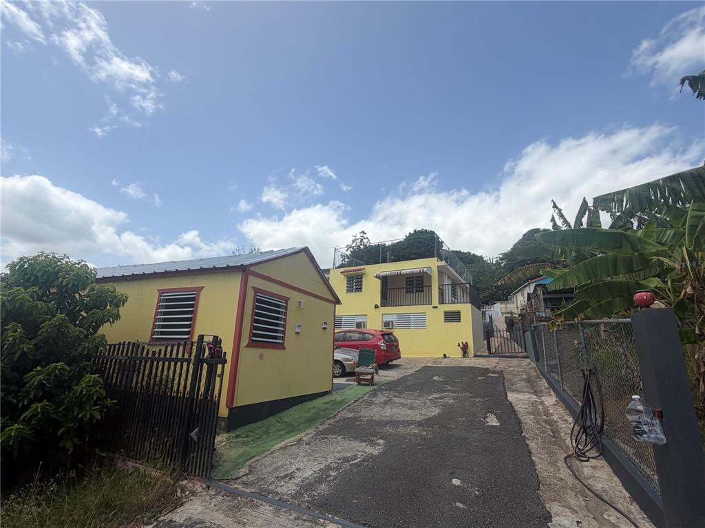 A yellow house with a driveway and a detached structure under a blue sky — 1 ANTONIO DE GRACIA, TOA ALTA, PR
