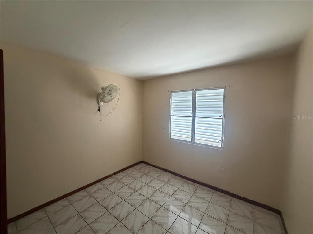 An empty room features light-colored walls, tiled flooring, and a wall-mounted fan — 1 ANTONIO DE GRACIA, TOA ALTA, PR