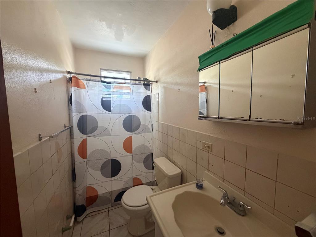 A bathroom features a tiled shower area, a pedestal sink, and a mirrored medicine cabinet — 1 ANTONIO DE GRACIA, TOA ALTA, PR