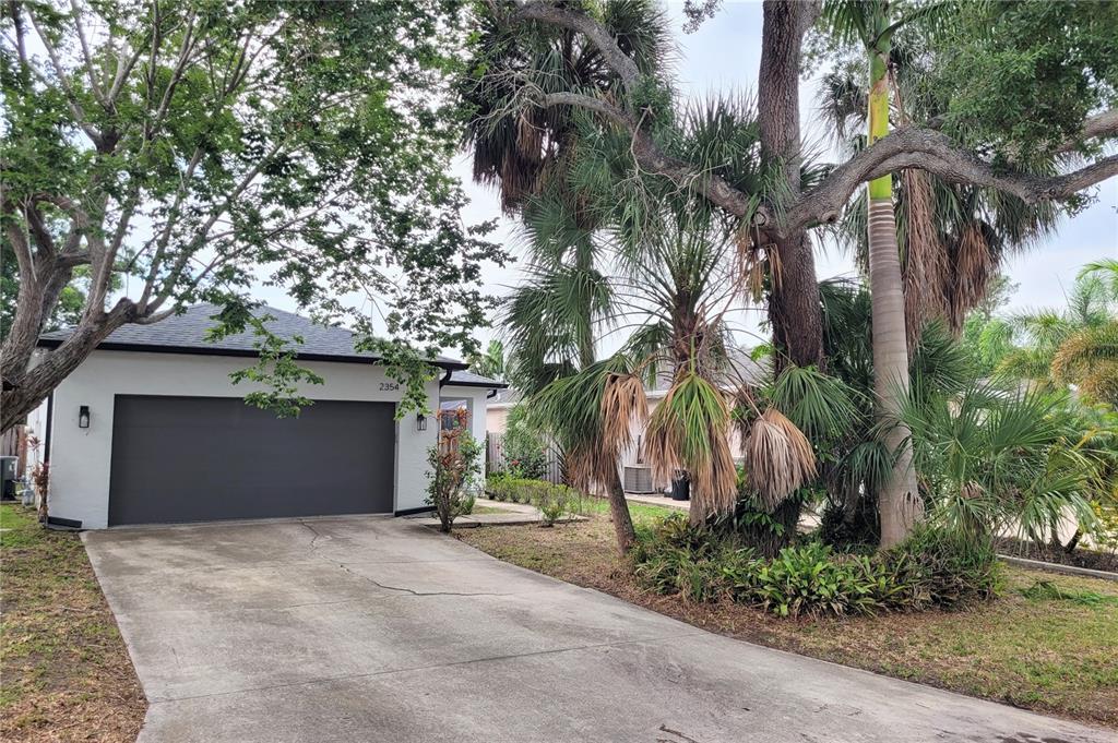 A white house with a dark garage door and palm trees in the front yard — 2354 TAMI SOLA STREET, SARASOTA, FL