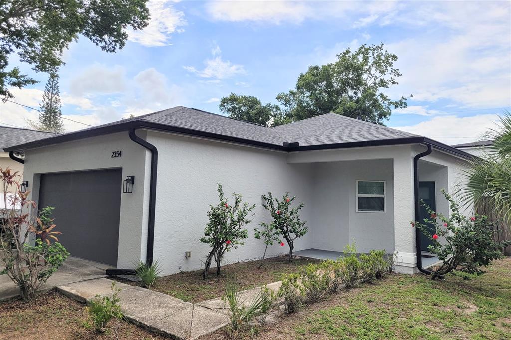 A single-story house with a gray stucco exterior, a dark garage door, and a covered entryway — 2354 TAMI SOLA STREET, SARASOTA, FL