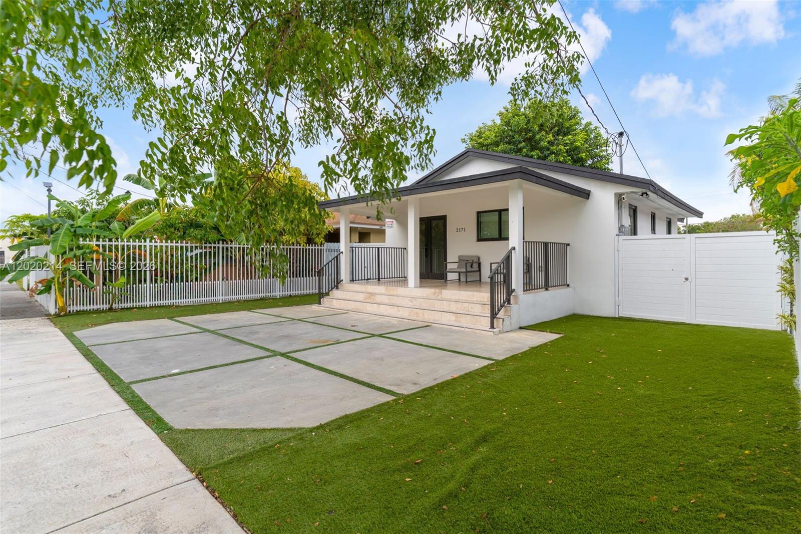 A white house with a covered porch, concrete driveway, and artificial turf lawn — 2171 NW 49th St, Miami FL 33142, MIAMI, FL