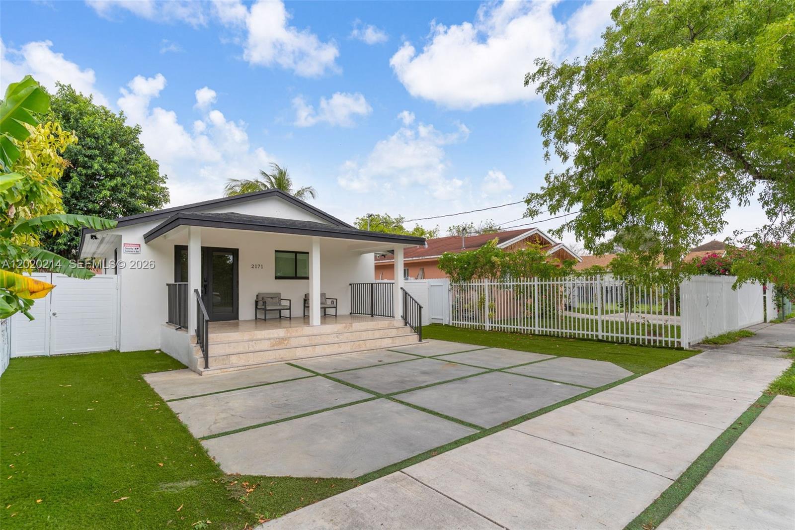 A single-story white house features a covered front porch, stone steps, and a concrete driveway — 2171 NW 49th St, Miami FL 33142, MIAMI, FL