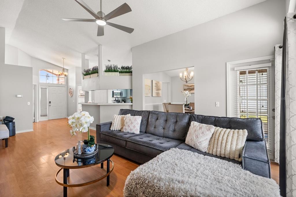 A living room features a gray sectional sofa, a round coffee table, and hardwood flooring — 3114 DELLCREST PLACE, LAKE MARY, FL