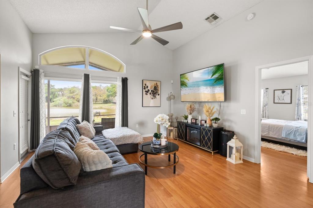 A living room with wood floors, a vaulted ceiling, a ceiling fan, and a lake view — 3114 DELLCREST PLACE, LAKE MARY, FL