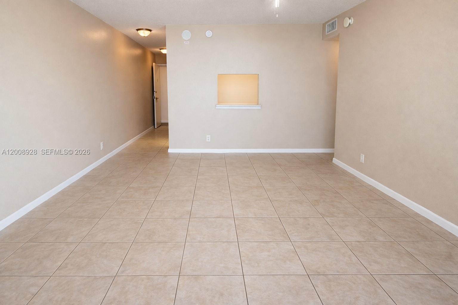 An empty room features beige walls, light-colored tile flooring, and a small wall cutout — 470 Executive Center Dr # 2D, West Palm Beach FL 33401, WEST PALM BEACH, FL
