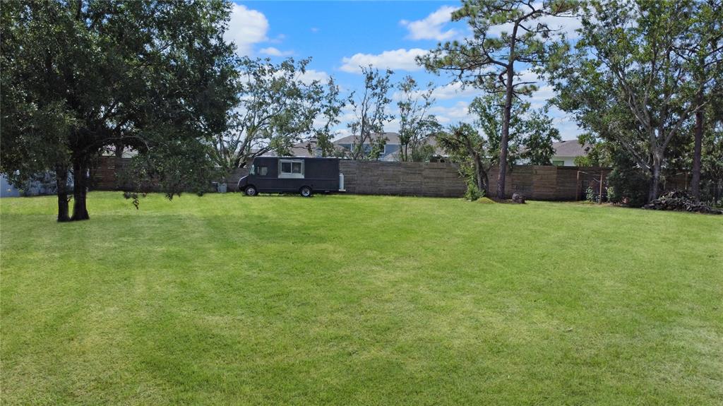 A large, grassy backyard features a dark food truck parked against a wooden fence — CITRUS STREET, KISSIMMEE, FL