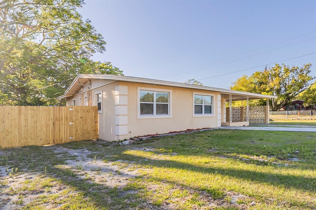 A single-story house with a tan exterior, white trim, and a wooden fence on the side — 4320 MEADOWBROOK AVENUE, ORLANDO, FL