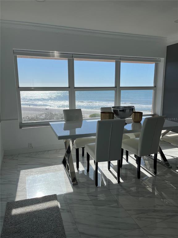 A dining area with a white table and chairs overlooks a beach and the ocean — 880 MANDALAY AVENUE UNIT S302, CLEARWATER BEACH, FL