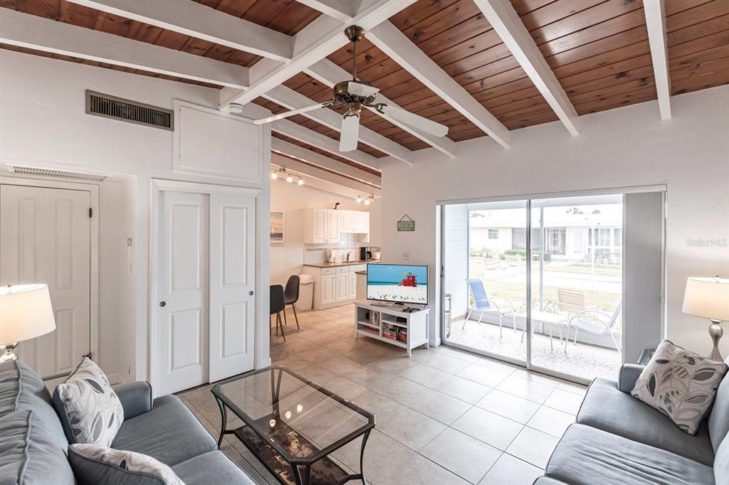 A living room with a wood-planked vaulted ceiling, tile floors, and a sliding glass door — 6006 MIDNIGHT PASS ROAD UNIT 5, SARASOTA, FL