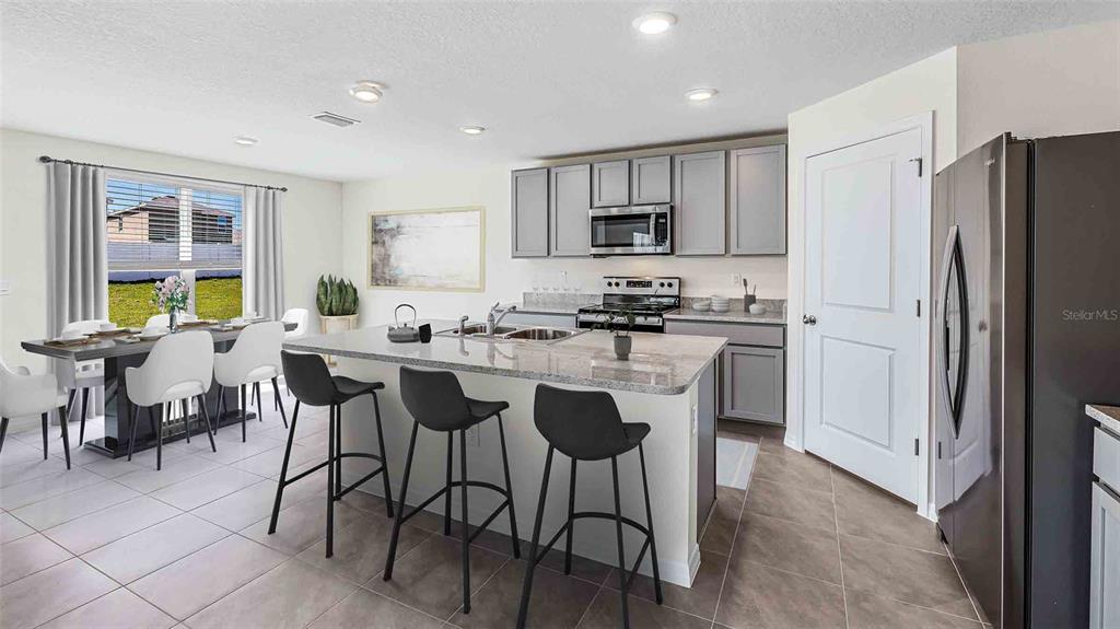 A kitchen with a granite-topped island, gray cabinetry, and an adjacent dining area — 10479 TUCKER ROAD, WEEKI WACHEE, FL