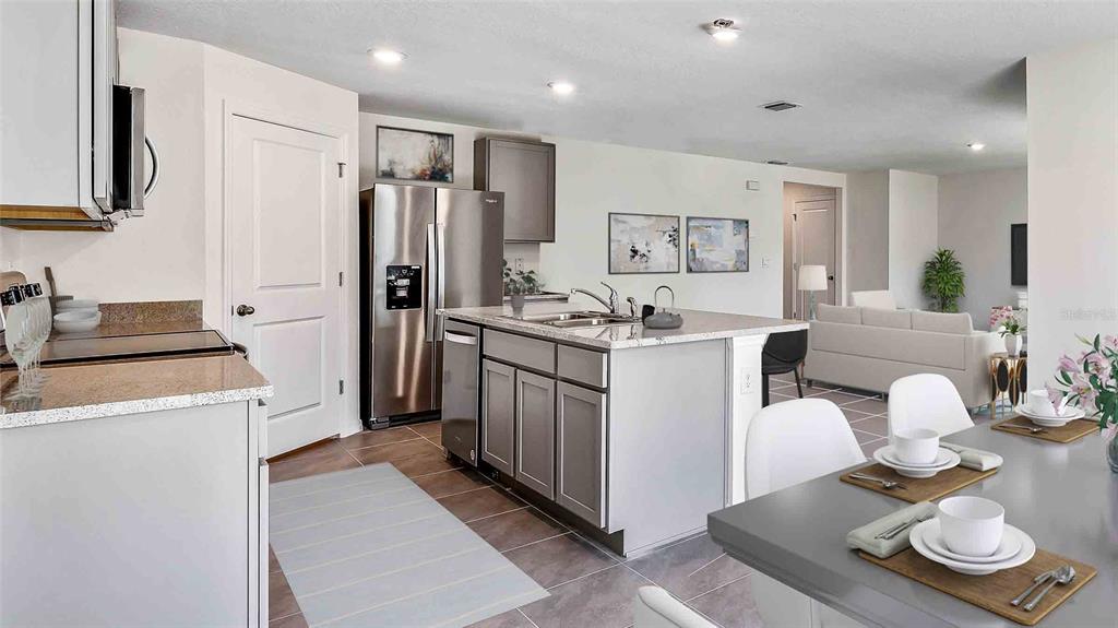 A modern kitchen features stainless steel appliances, a central island, and an adjacent dining area — 10479 TUCKER ROAD, WEEKI WACHEE, FL