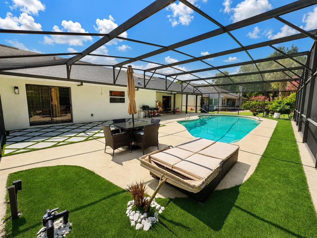 A screened-in patio features a swimming pool, dining set, lounge furniture, and artificial turf — 6350 OAK MEADOW BEND, ORLANDO, FL