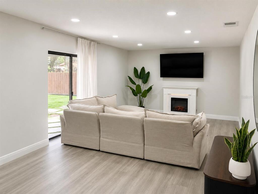 A living room features a sectional sofa, a fireplace with a television, and sliding doors — 6350 OAK MEADOW BEND, ORLANDO, FL