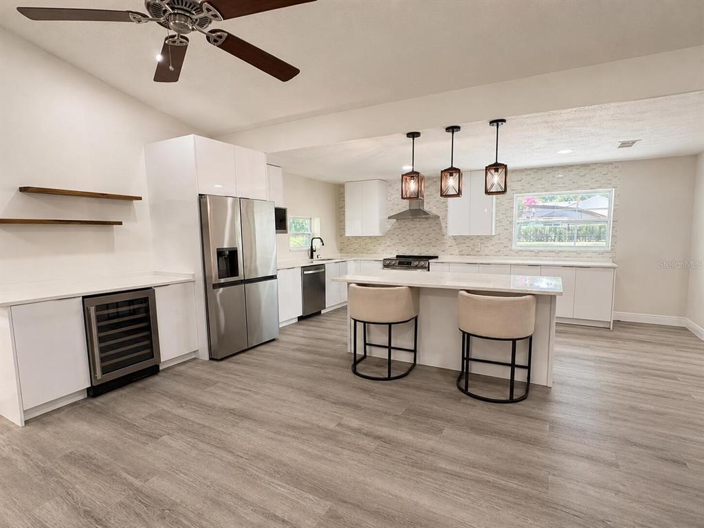 A modern kitchen features white cabinetry, a stainless steel refrigerator, and a central island — 6350 OAK MEADOW BEND, ORLANDO, FL