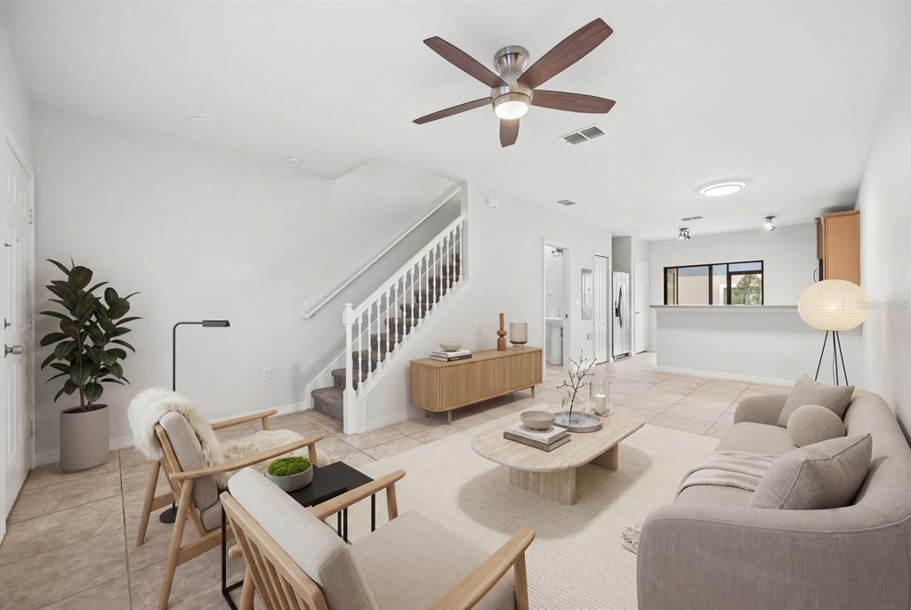 A living room features a staircase, light tile flooring, a ceiling fan, and neutral furniture — 1121 TRILLIUM PARK LANE, SANFORD, FL