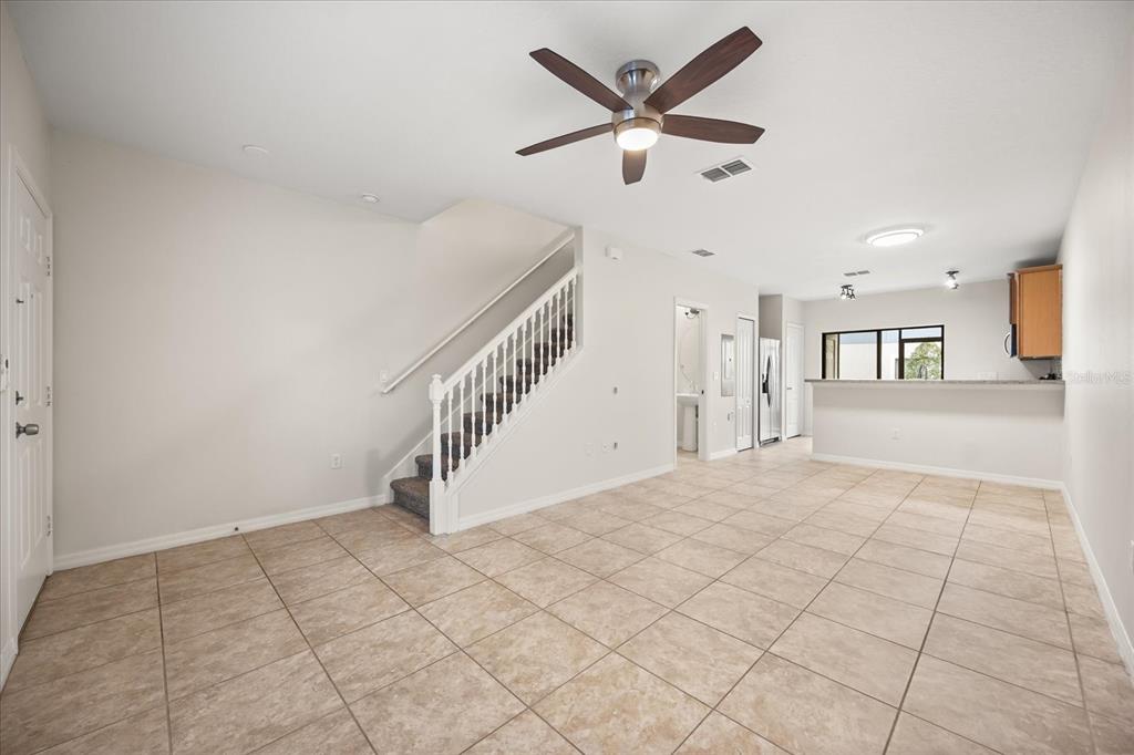An open-concept living area features tile flooring, a staircase, and a kitchen with a bar — 1121 TRILLIUM PARK LANE, SANFORD, FL