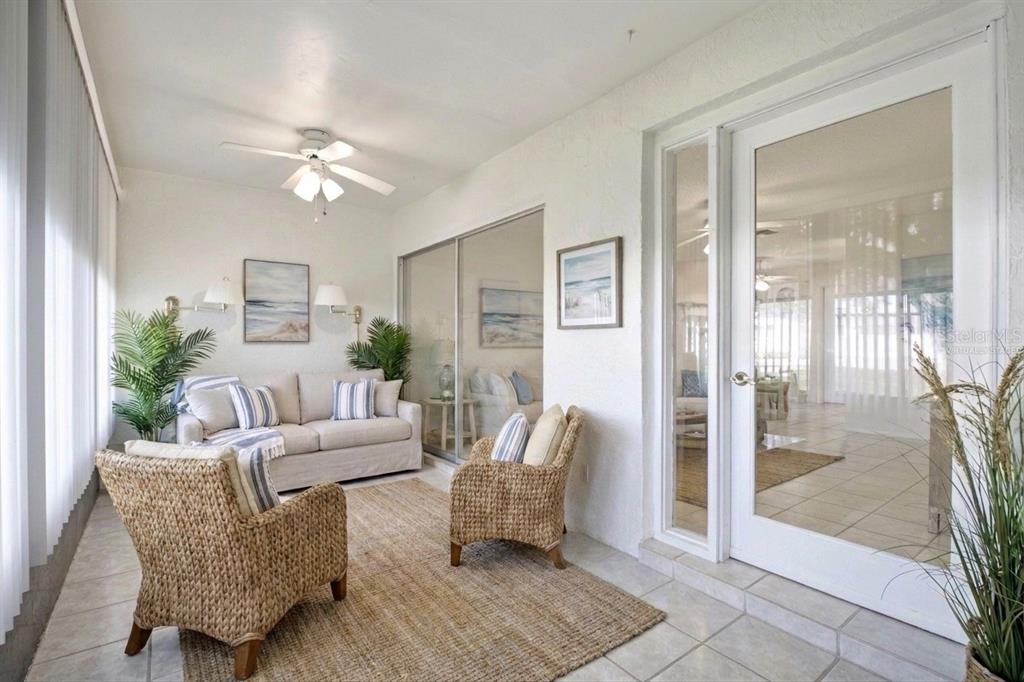 A sunroom features tile flooring, wicker armchairs, a sofa, and a glass door to indoors — 1335 QUEEN ANNE DRIVE UNIT C, PALM HARBOR, FL