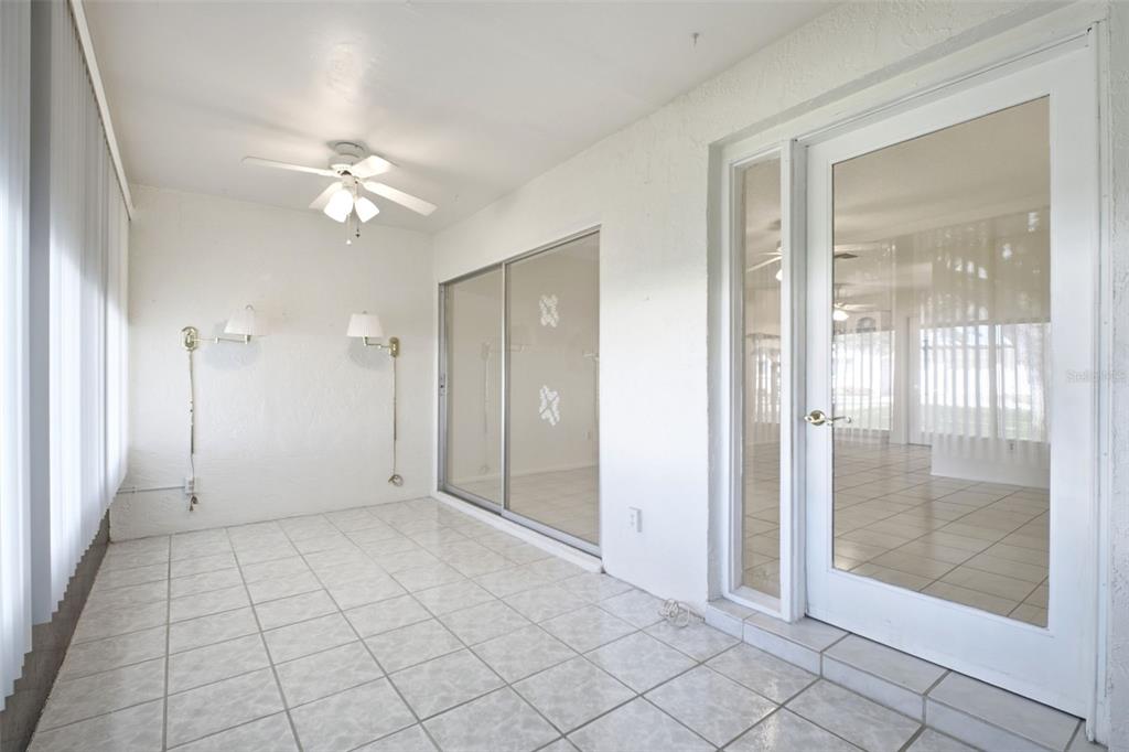 A sunroom with white tile floors, a ceiling fan, sliding glass doors, and a glass door — 1335 QUEEN ANNE DRIVE UNIT C, PALM HARBOR, FL