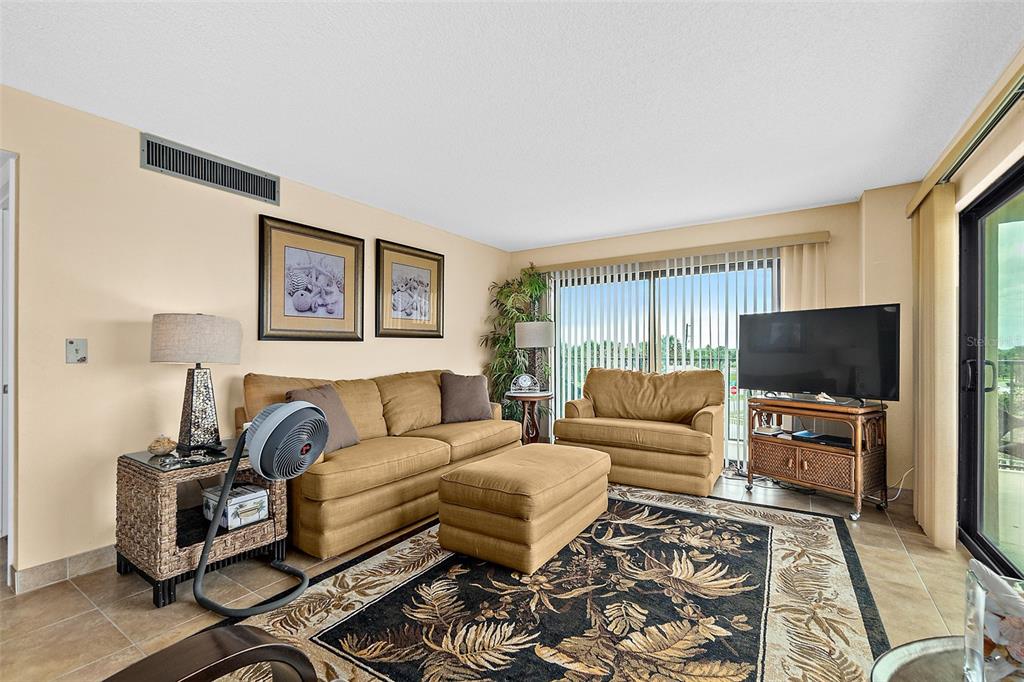 A living room features tan furniture, a patterned area rug, and a sliding glass door — 3600 S OCEAN SHORE BOULEVARD UNIT 211, FLAGLER BEACH, FL