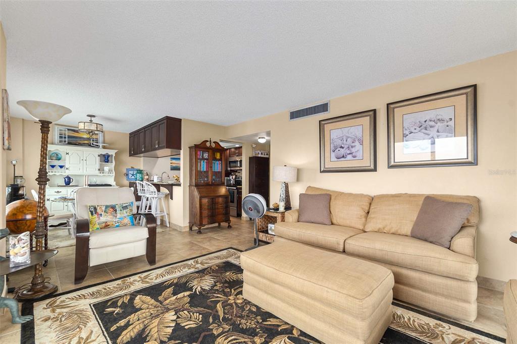A living room with a beige sofa, ottoman, patterned rug, and an adjacent dining area — 3600 S OCEAN SHORE BOULEVARD UNIT 211, FLAGLER BEACH, FL