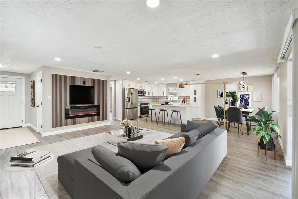 An open-concept living room and kitchen featuring a slatted wood accent wall with a fireplace — 2258 GEORGE WYTHE ROAD, ORANGE PARK, FL