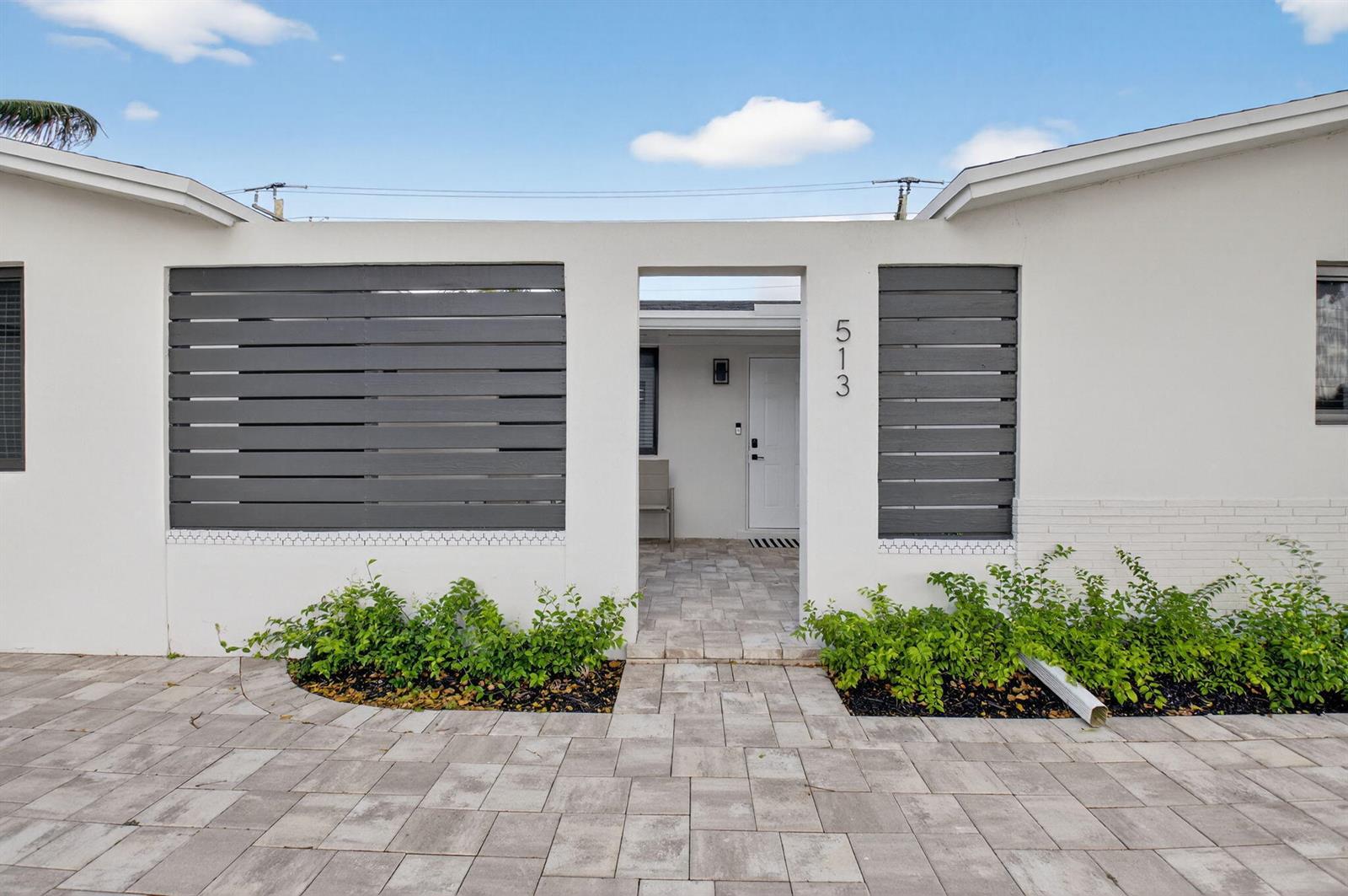 A white exterior wall features dark horizontal slats, a central entryway, and a paved walkway — 513 Lindell Boulevard, Delray Beach FL 33444, DELRAY BEACH, FL