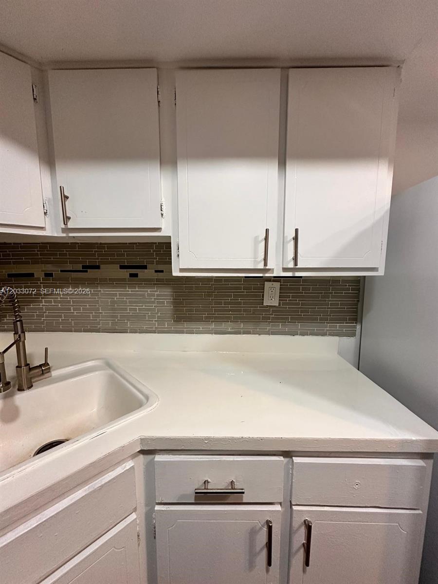 A kitchen features white cabinets, a light-colored countertop, and a horizontal-tiled backsplash — 5540 SW 38th Ct # 0, West Park FL 33023, WEST PARK, FL