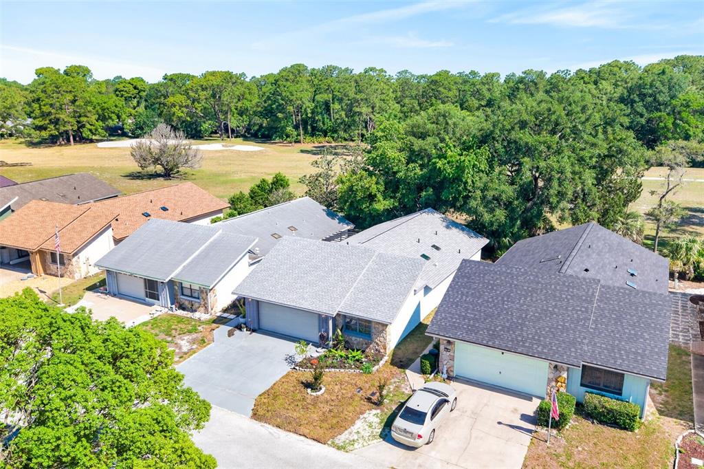 An aerial view shows several suburban houses with gray roofs and driveways near a golf course — 16 GOLFVIEW COURT, HOMOSASSA, FL
