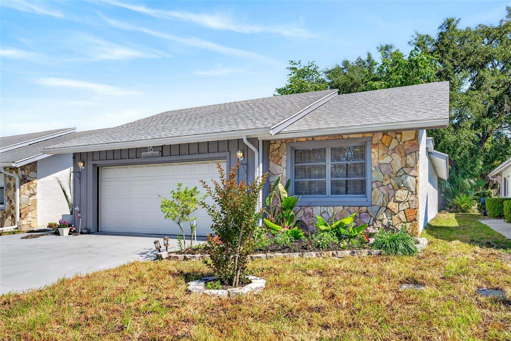 A single-story house features a gray garage, stone facade, and a landscaped front yard — 16 GOLFVIEW COURT, HOMOSASSA, FL