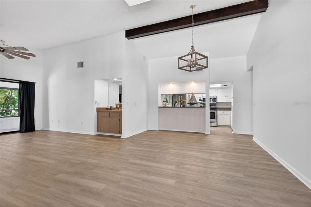 A living room features light wood-look flooring, a vaulted ceiling with a beam, and a bar — 16 GOLFVIEW COURT, HOMOSASSA, FL