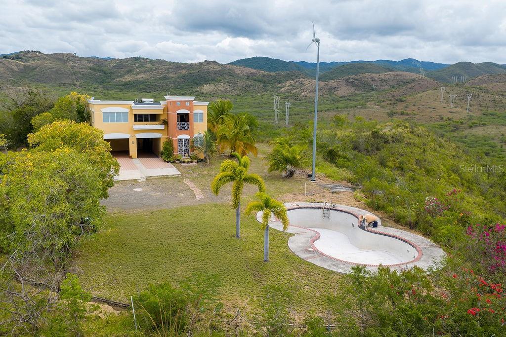 An aerial view shows a two-story house with a pool and wind turbine in a landscape — 706 St SECTOT LA JULIA, SALINAS, PR