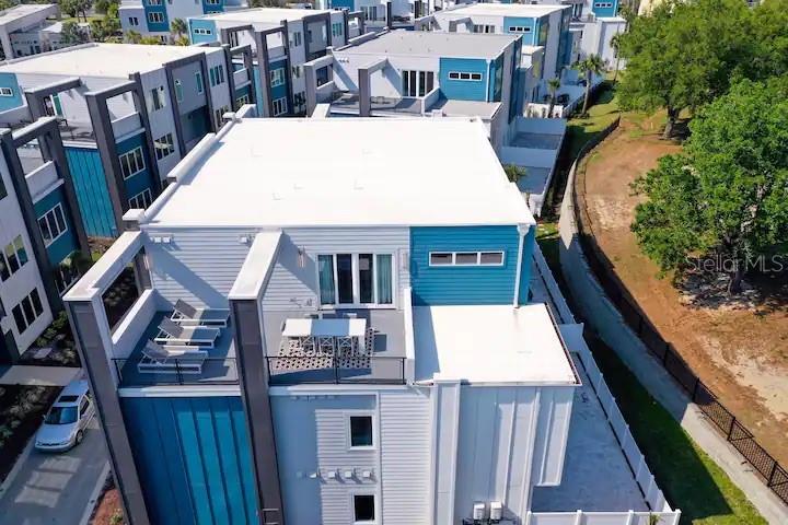 An aerial view shows a modern multi-story townhouse with a rooftop terrace and balcony — 7740 SANDY RIDGE DRIVE UNIT 223, KISSIMMEE, FL