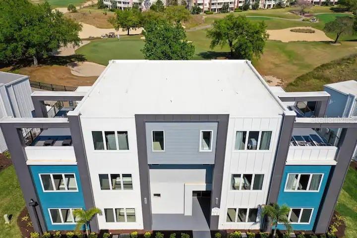 An aerial view of a modern three-story apartment building overlooking a golf course — 7740 SANDY RIDGE DRIVE UNIT 223, KISSIMMEE, FL