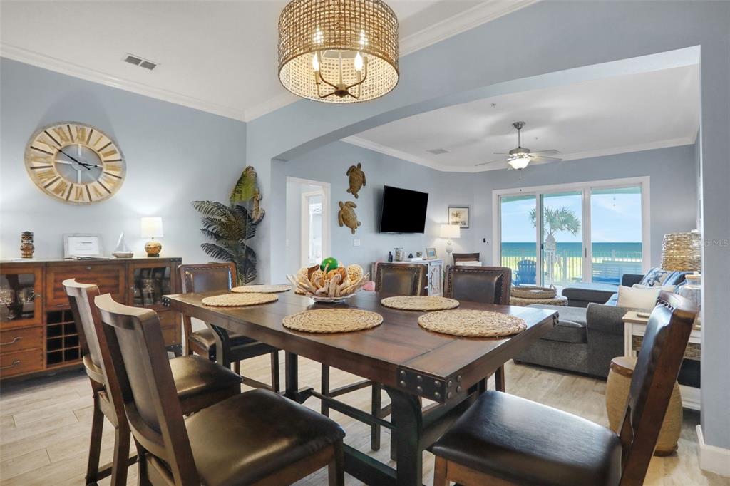 A dining room with a wooden table and chairs opens into a living area overlooking the ocean — 700 CINNAMON BEACH WAY UNIT 624, PALM COAST, FL